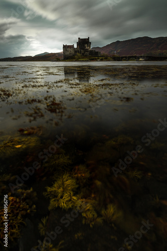 Eilean Donan Castle at Loch Duich with lake with seaweed and dramatic clouds on a moody autumn day (Dornie, Scotland, United Kingdom, Europe)