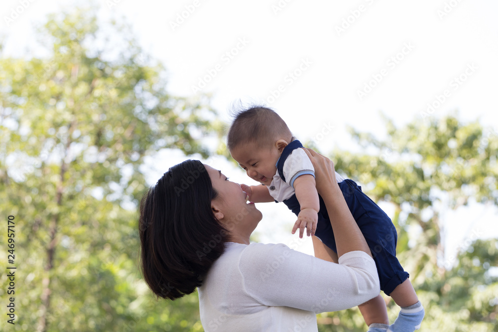 Happy young mother playing and having fun with little baby son in the green garden summer day. Family in the park concept Happy young mother playing and having fun with little baby son in the green garden summer day. Family in the park concept