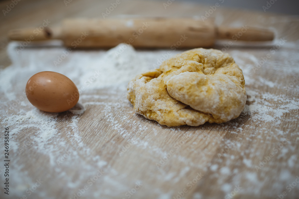 The girl prepares the dough for homemade noodles. On the table there is everything you need. The girl prepares the dough for homemade noodles. On the table there is everything you need.