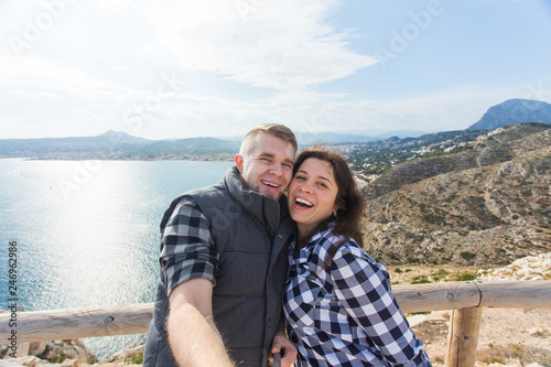 Travel, vacation and holiday concept - Happy couple taking selfie over beautiful landscape