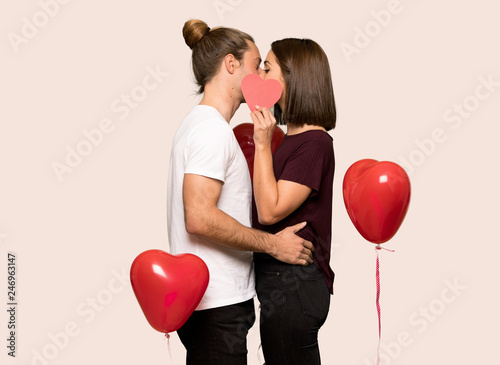 Couple in valentine day holding a heart symbol and kissing over isolated background