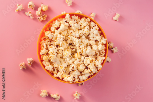 A bowl with popcorn on pink background.