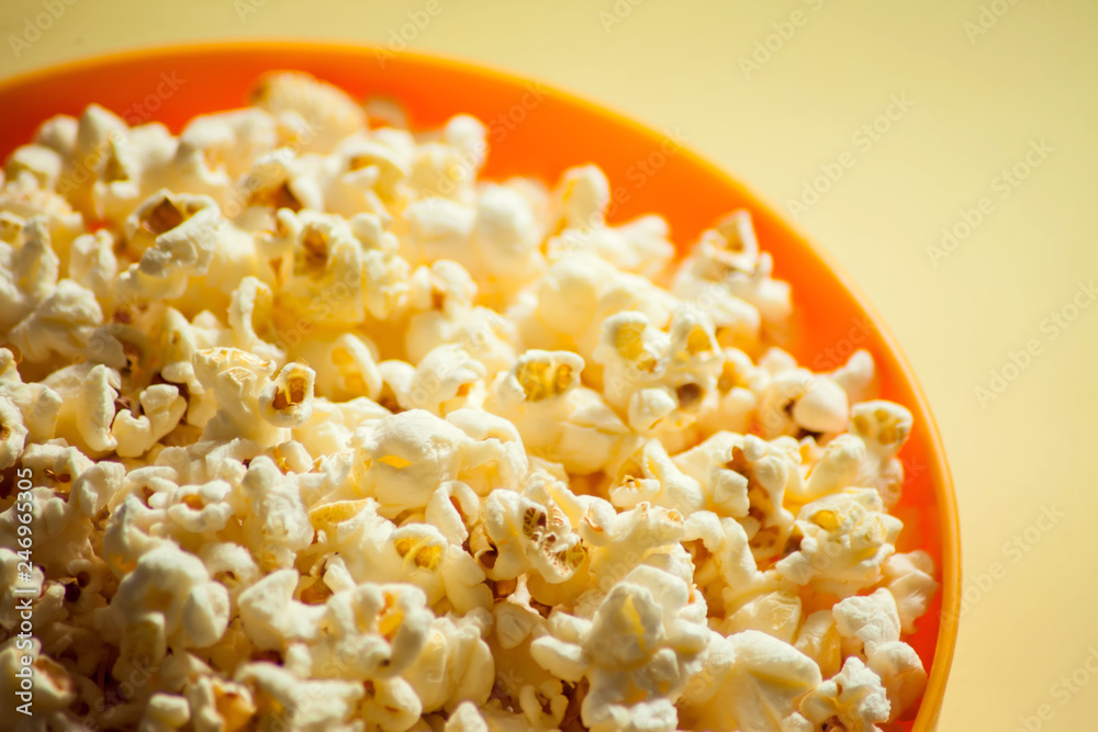 An orange bowl with popcorn isolated on yellow background An orange bowl with popcorn isolated on yellow background