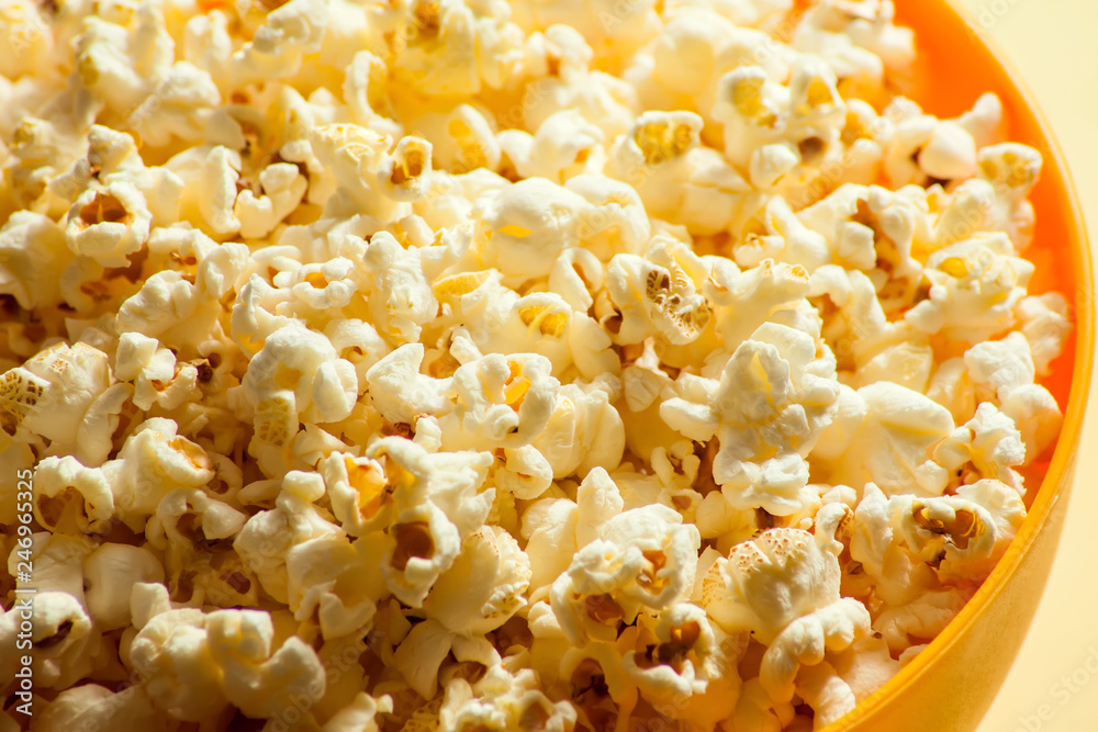 An orange bowl with popcorn isolated on yellow background An orange bowl with popcorn isolated on yellow background