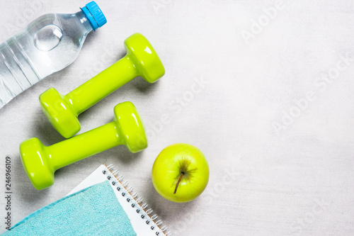 Dumbbells, notepad, water and apple top view. 