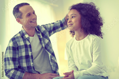 Playful father excitedly feeling his adopted daughters fluffy hair.