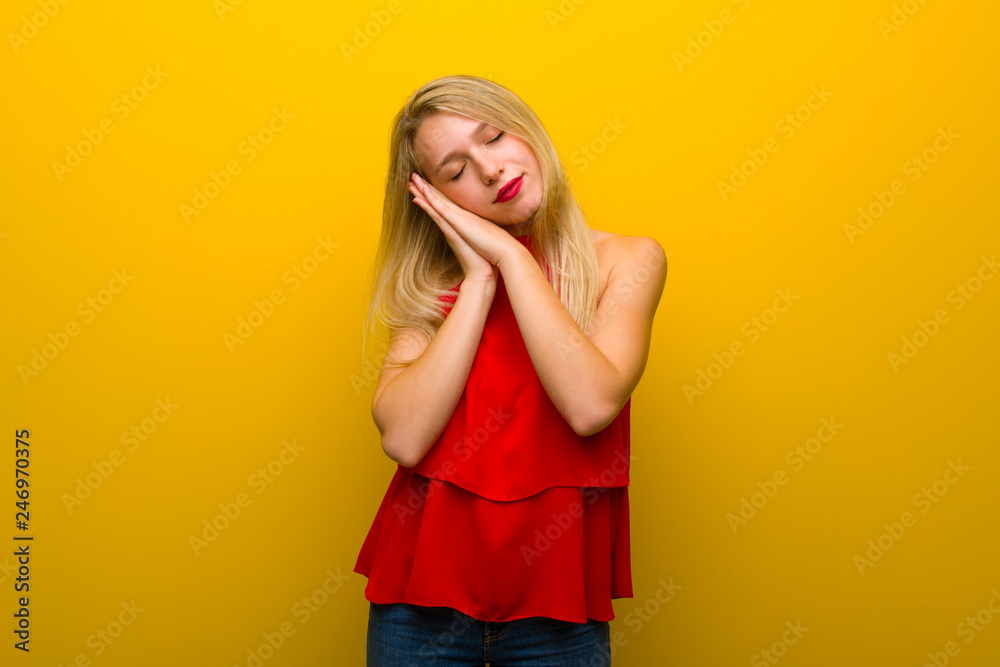 Young girl with red dress over yellow wall making sleep gesture in dorable expression Young girl with red dress over yellow wall making sleep gesture in dorable expression