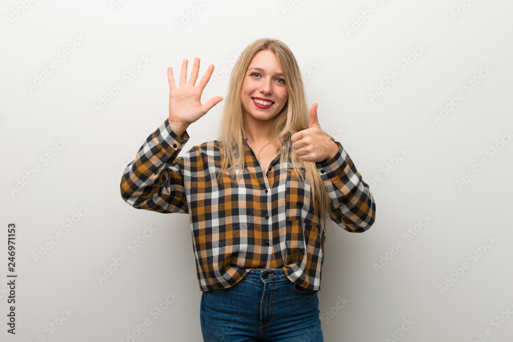 Blonde young girl over white wall counting six with fingers Blonde young girl over white wall counting six with fingers