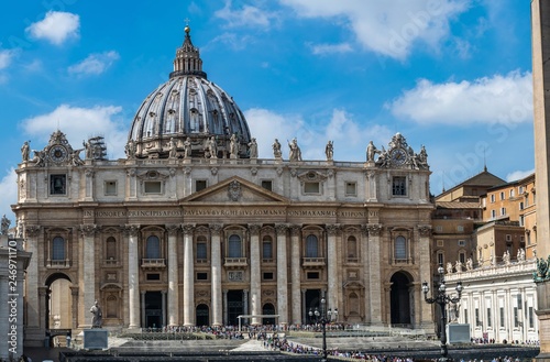 panoramic front view on Dome of St. Peter's Basilica with statues of apostles chapel with bell and old clock in Vatican City, Italy photo