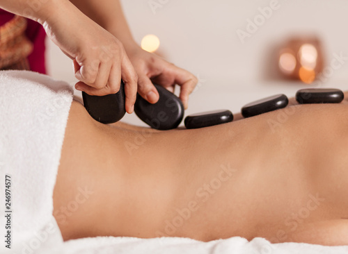 Foto masseur putting black stones on the clien's back