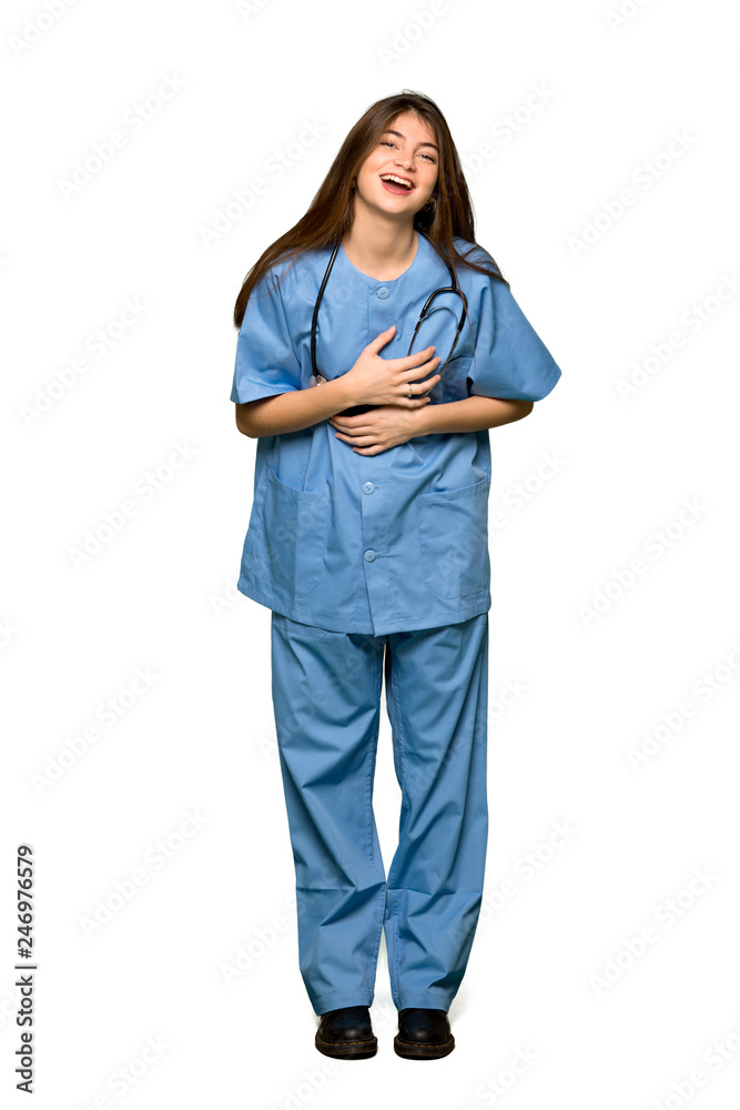 Full-length shot of Young nurse smiling a lot while putting hands on chest on isolated white background