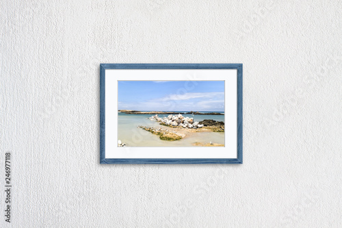 Frame mock up with oceanview and seagulls picture, grey blue realistic wooden framework isolated on white plastered wall
