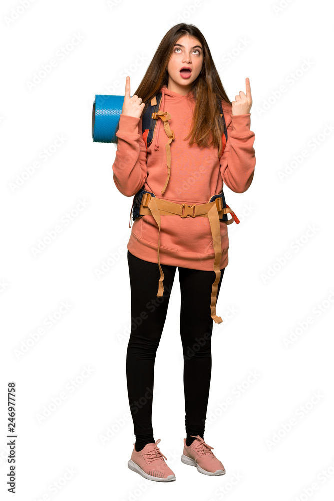 Full-length shot of Hiker girl surprised and pointing up on isolated white background Full-length shot of Hiker girl surprised and pointing up on isolated white background