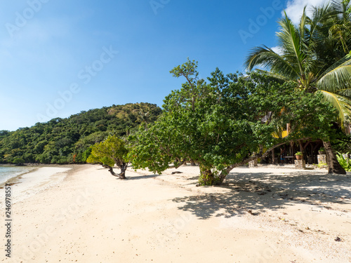 Tropical beach with palm trees, blue sky, turquoise water and white sand. Paradise. Philippines, Palawan, Banana island. Wide angle, horizontal. November, 2018