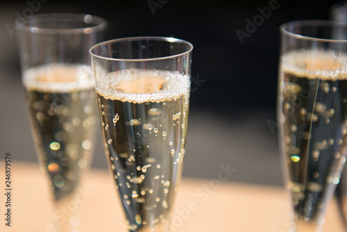 Plastic glass of champagne with sparkling bubbles and two other glasses in background