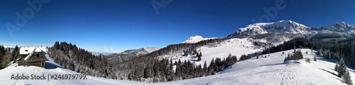 Panoramic winter landscape with old wooden hut in the mountains.
