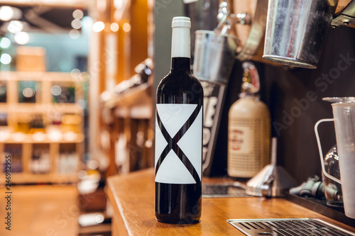 Black wine bottle with label and white cap in wine shop