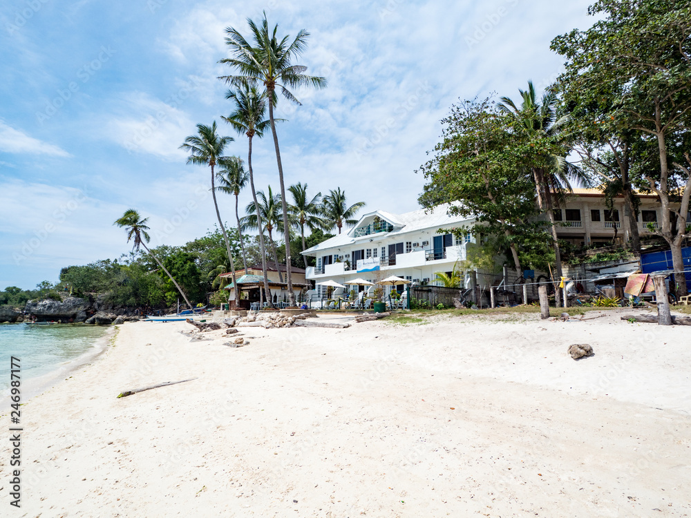 Beautiful tropical beach background from Alona Beach at Panglao Bohol island with beach chairs on the white sand beach with cloudy blue sky and palm trees. Travel Vacation, november 2018