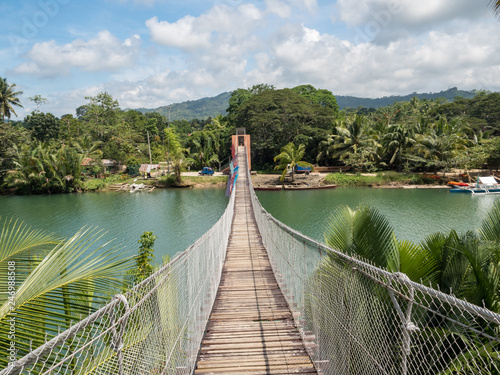Fototapeta Naklejka Na Ścianę i Meble -  Pedestrian hanging bridge over river in tropical forest, Bohol, Philippines. November, 2018