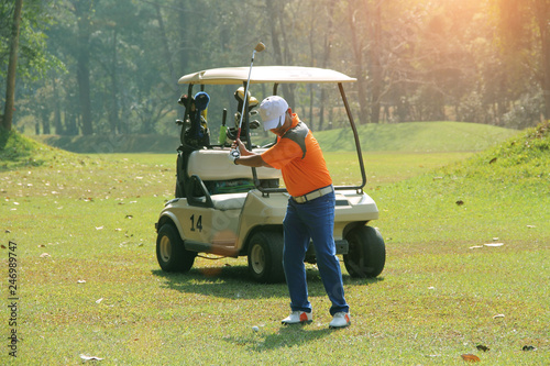 Golfer playing golf beside the golfcar in beautiful golf course in the evening golf course with sunshine