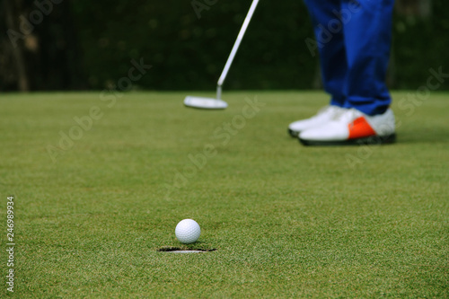 Golfer putting golf ball on the green golf