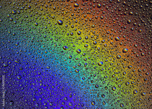 Drops of water on the glass  with the reflection of the rainbow.