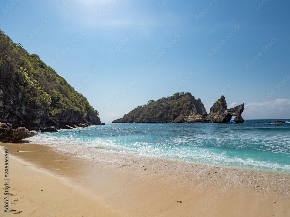 Exotic destination background with tuquoise sea water, palm trees, white sand beach and golden sun light. Warm natural colours. Top view. Atuh beach, Nusa Penida Island, Bali, Indonesia. October, 2018