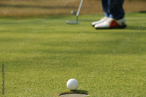 Golfer putting golf ball on the green golf