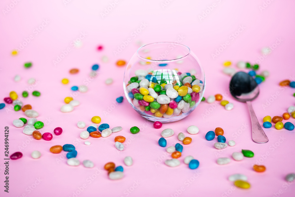 colorful candy in clear wrappers piled in a glass vase isolated on pink background colorful candy in clear wrappers piled in a glass vase isolated on pink background