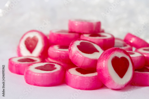 Pink and white candys with red hearts on white background
