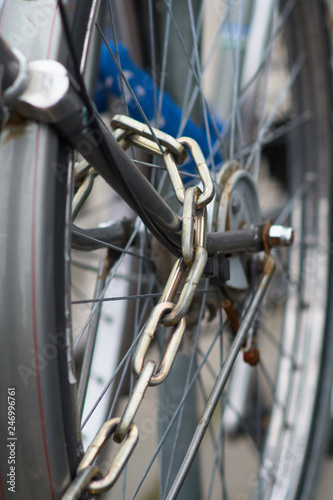 Detail of an old rusty bicycle with a safe iron chain locked on the wheel. © anokato