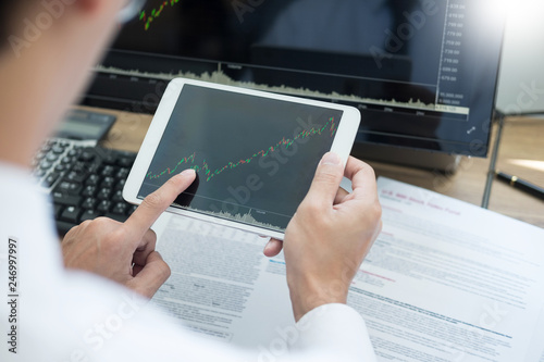 Stock exchange trader Analyzing Graphs chart or data On Multiple Screens in office.