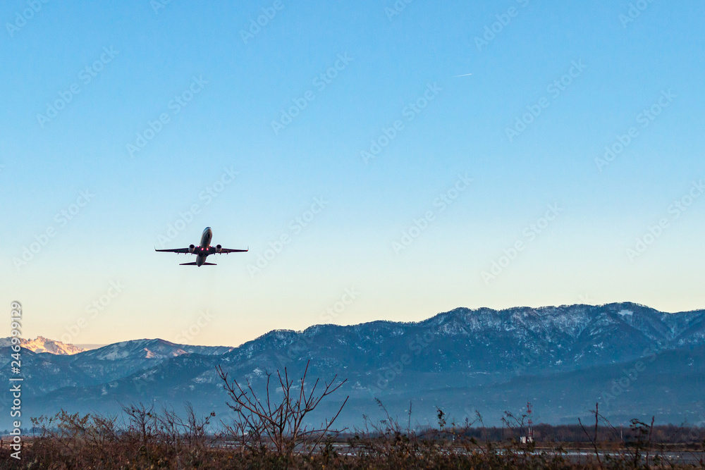 Plane taking off from a runway against a blue sky and mountains