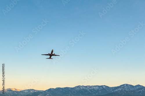 Flying plane on a background of blue sky and mountains