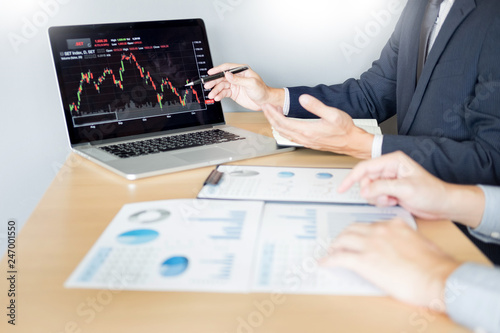 Stock traders looking at finance analysis marketing report trading stocks online in office.
