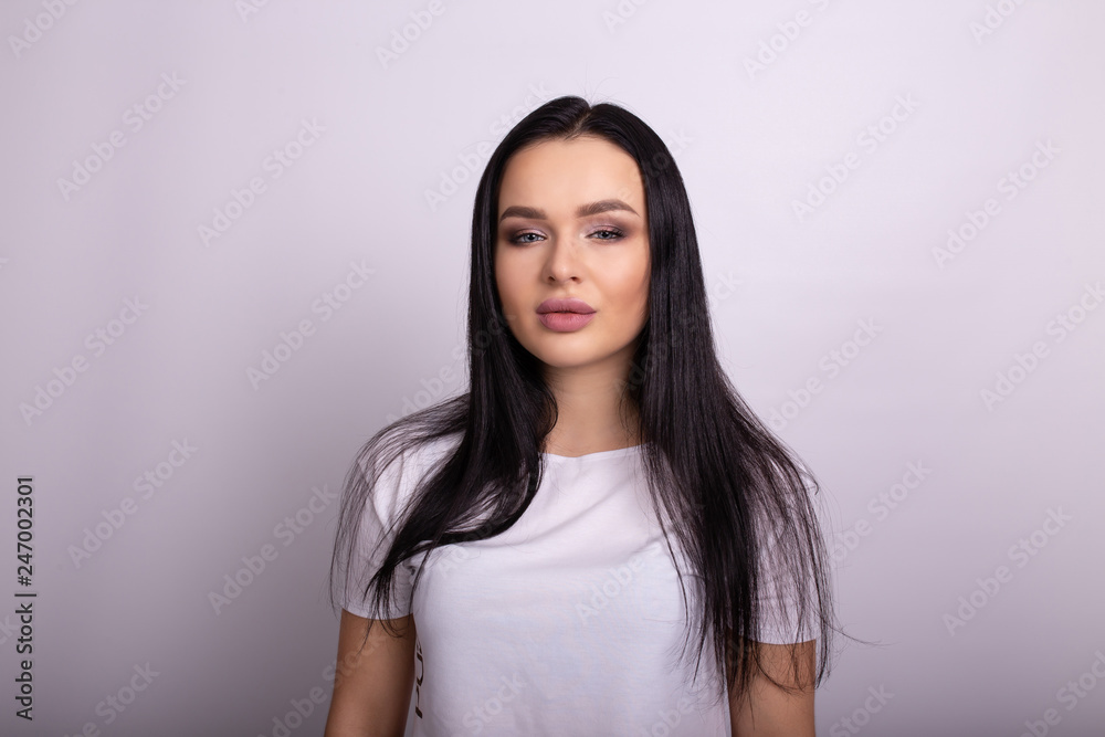 Close up portrait of stylish young pretty woman smiling in white t-shirt, isolated, natural look, long brown hair Close up portrait of stylish young pretty woman smiling in white t-shirt, isolated, natural look, long brown hair