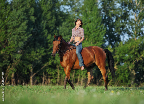 Beautiful cowgirl bareback ride her horse in woods glade at sunset 