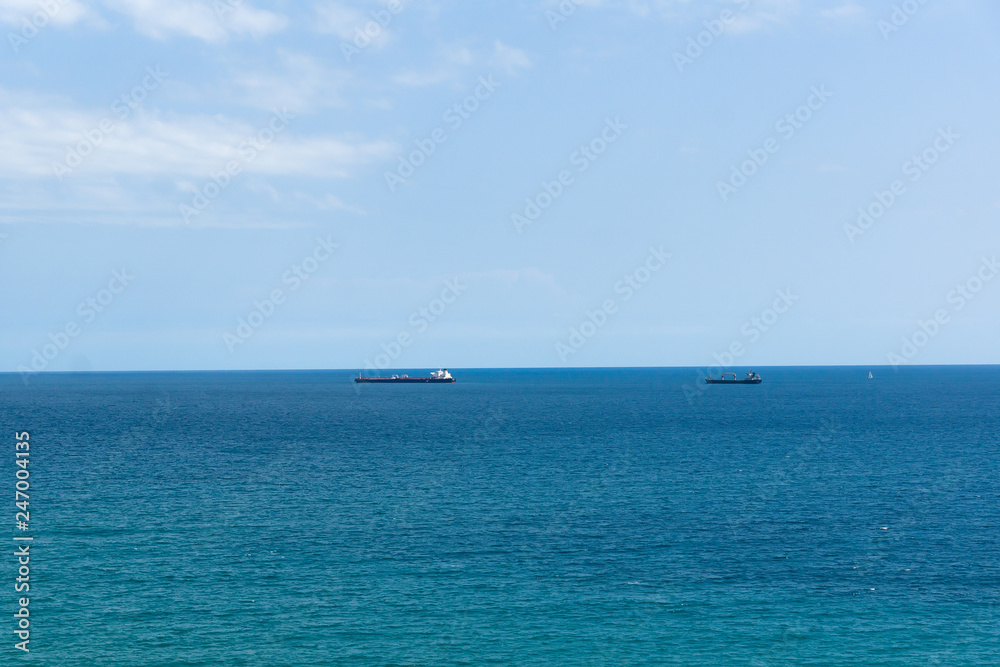 blue sea surface with small ships on the horizon