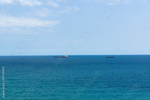 blue sea surface with small ships on the horizon