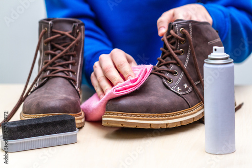 Photography A person is cleaning men's suede casual boots with brush, rag and spray