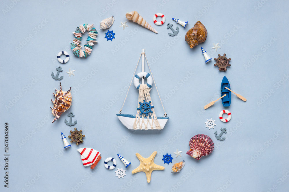 Round frame made of decorative items and miniature toys: seashells, seastars, vessel, boat, anchors, steering wheels, life buoys. Creative composition with ship. Summer vacation, sea travel concept