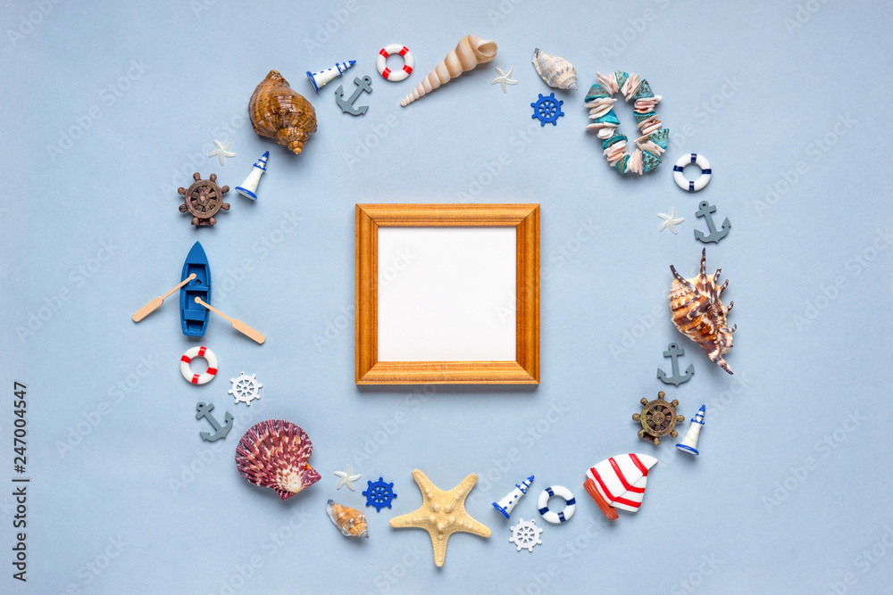 Obraz premium Round frame made of decorative items and miniature toys: seashells, seastars, vessel, boat, anchors, steering wheels, life buoys. Empty wooden photoframe, mock-up. Summer vacation, sea travel concept