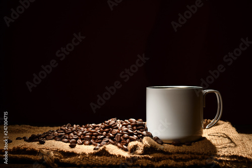 Cup of coffee and coffee beans on black background