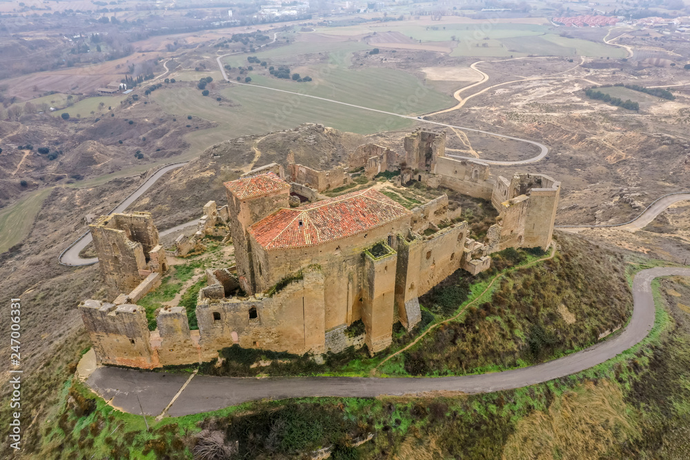 Aerial view of the ruined medieval abandoned Montearagon castle, namesake of the famous kingdom on a bare mountain top near Huesca, Aragon province Spain with stormy cloudy sky