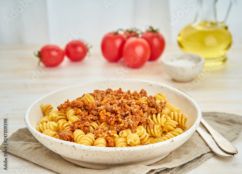 Bolognese pasta. Fusilli with tomato sauce, ground minced beef. Traditional italian cuisine. White wooden table. Side view.