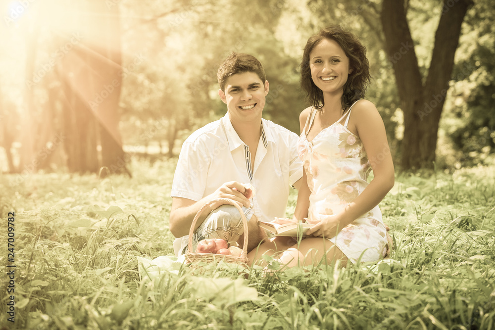 beautiful couple sitting in the grass looking into the camera smiling beautiful couple sitting in the grass looking into the camera smiling