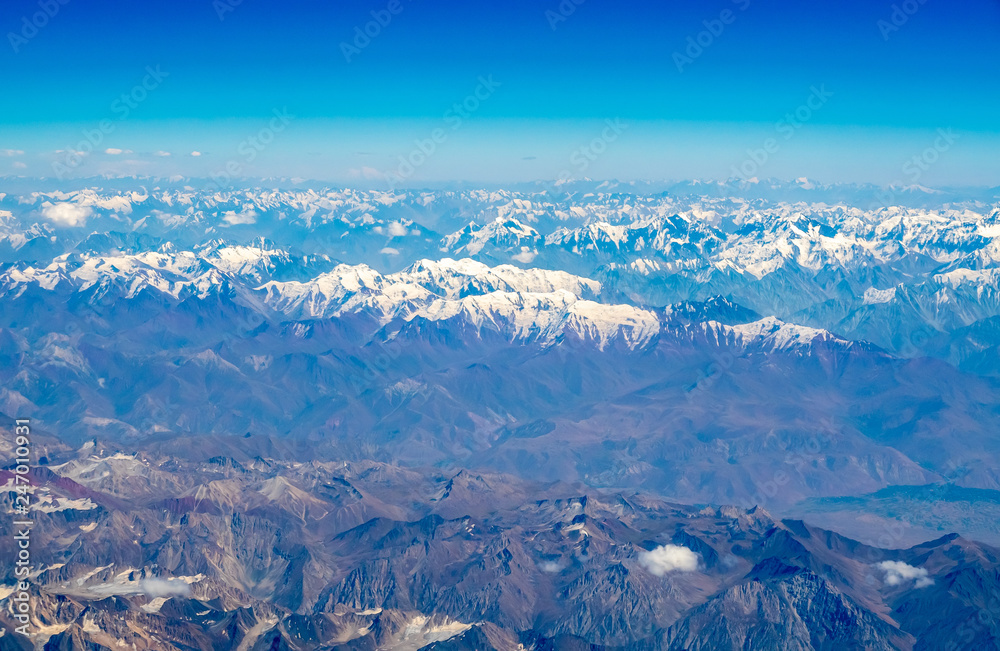 Fototapeta premium Mountains earth from aircraft under blue sky