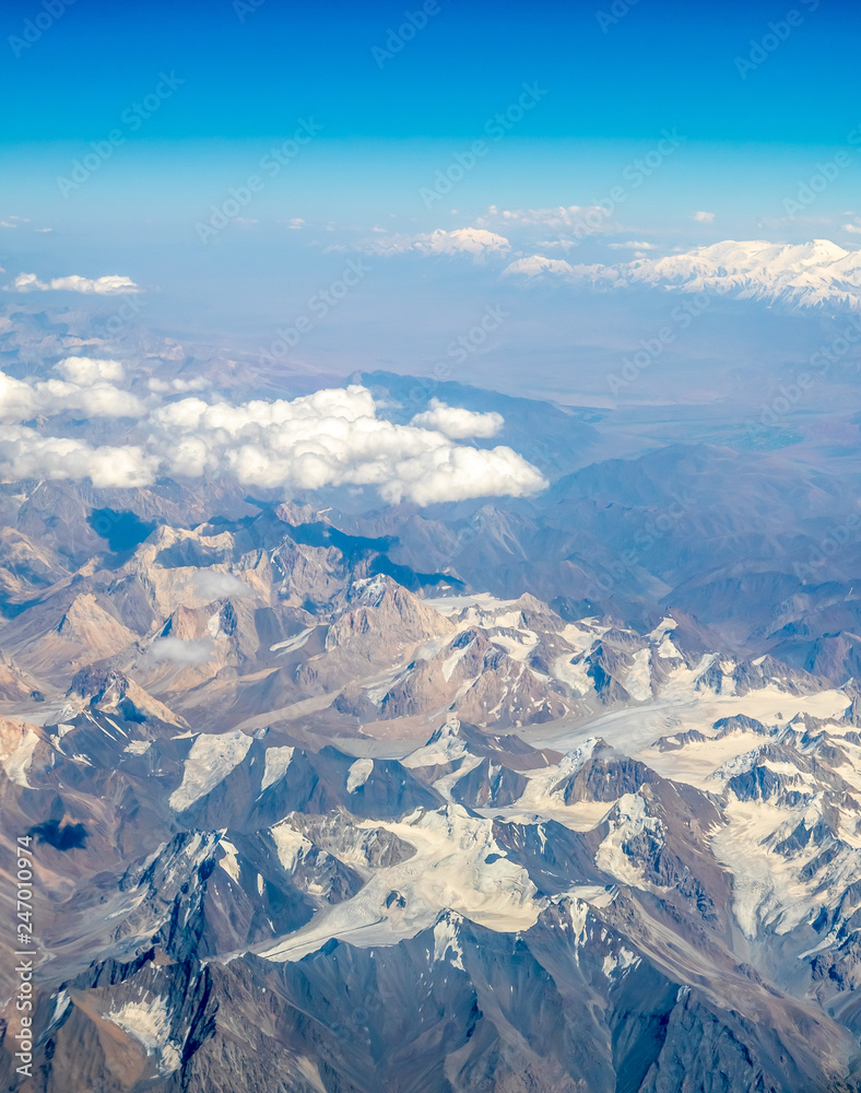 Fototapeta premium Mountains earth from aircraft under blue sky