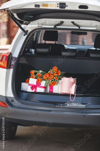 present boxes in the car. Gifts in automobile trunk. Tulip bouquet in the luggage boot.
