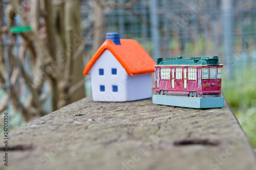Miniature soft toy house on concrete fence with a tram toy car
